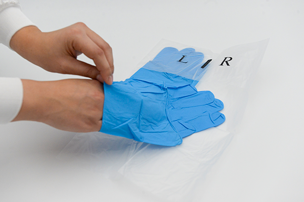 DYNOsense blueNitrile DW+ 400 sterileSie zieht die sterilen blauen Handschuhe an.